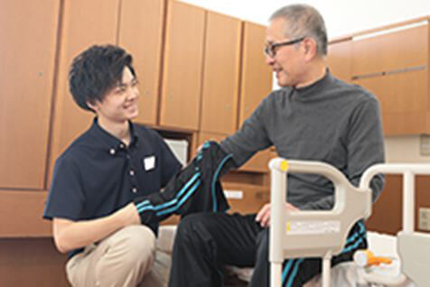 スタッフが患者さんのパジャマを日常着に着替えさせている様子